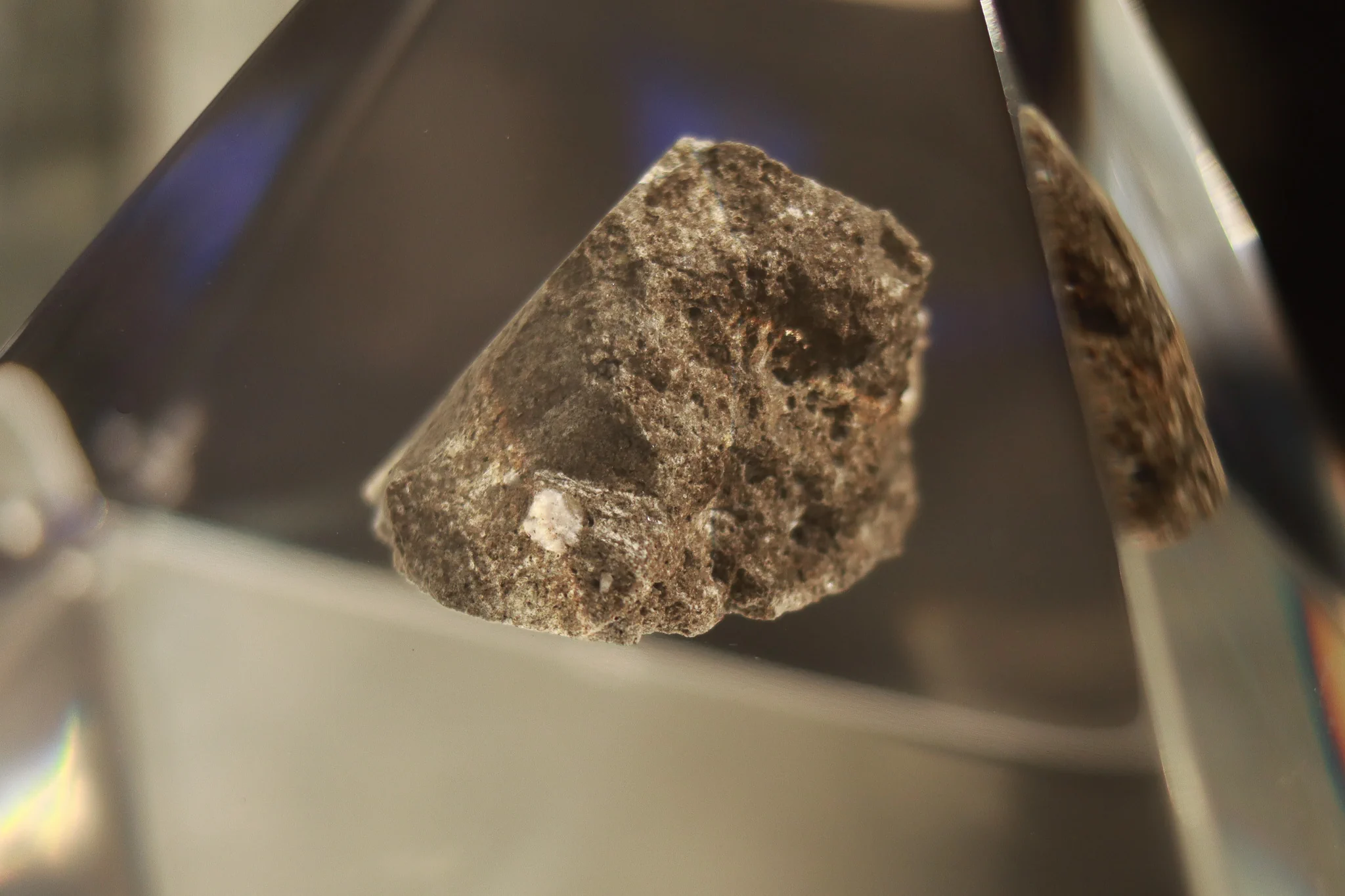 Small irregular lunar rock displayed inside a transparent protective case at Space Expo in Noordwijk