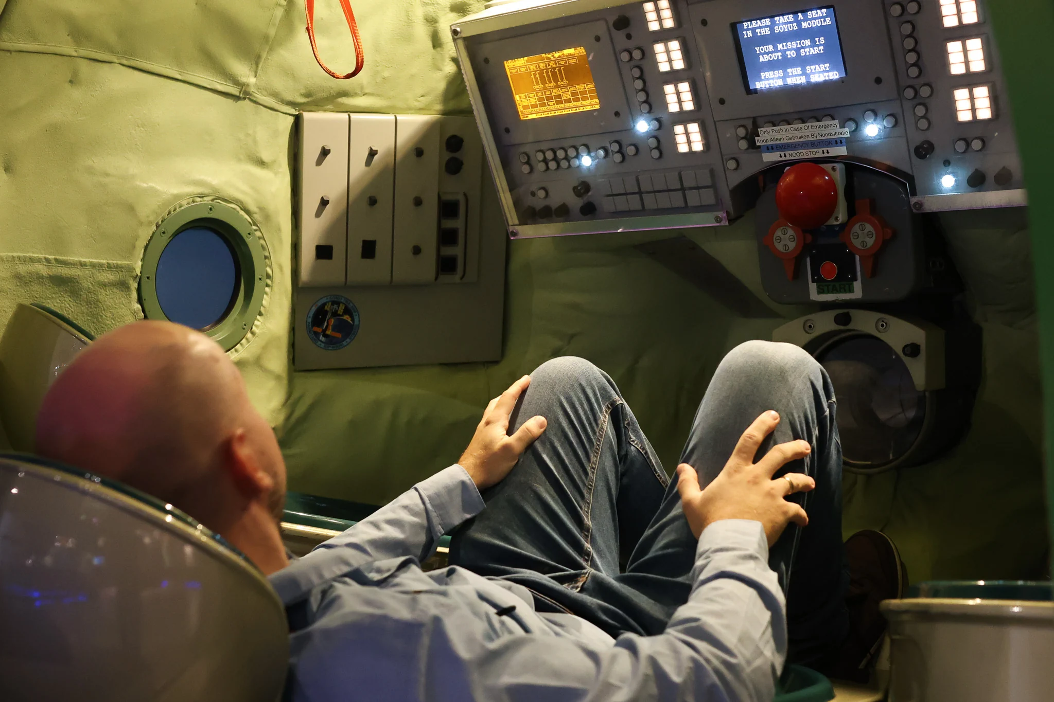 Paweł reclining inside a Soyuz spacecraft simulator surrounded by flight controls and equipment